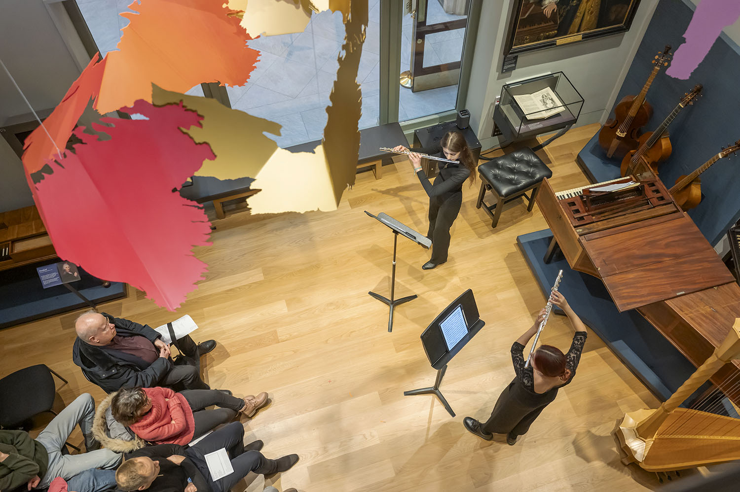 Two flute players photographed performing from the top level of the RCM Museum