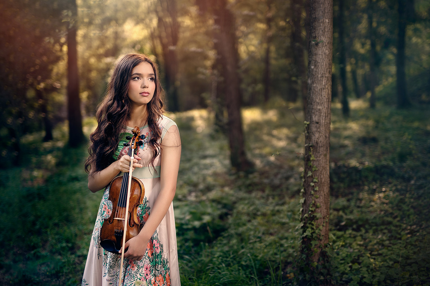 A woman standing in a forest and holding a violin