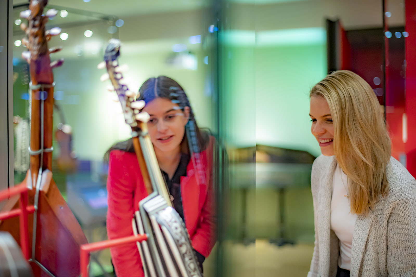 Two women looking at display cases of guitars in the RCM Museum
