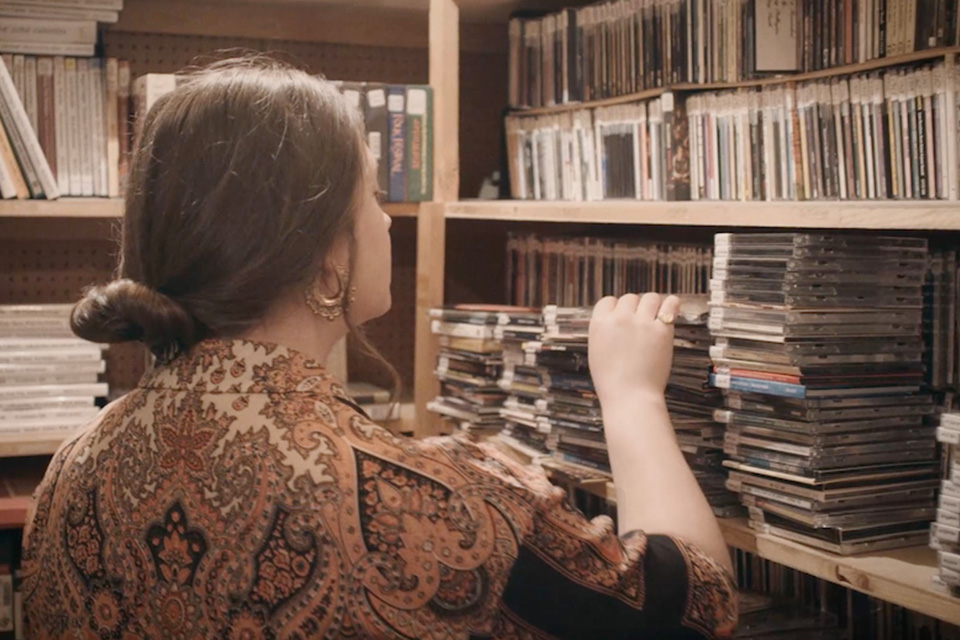 A woman sorts through books and recordings in a folk archive