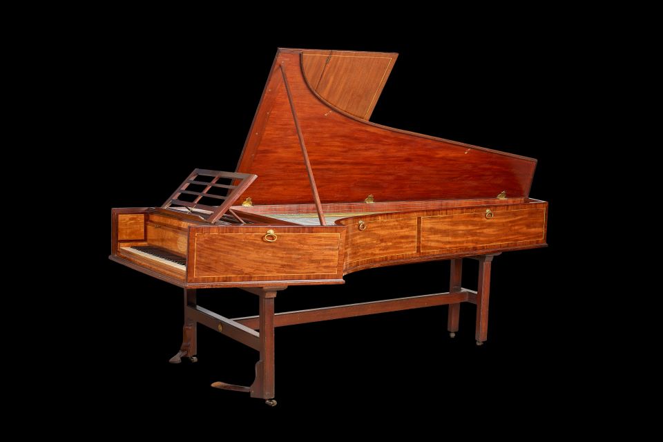A historical grand piano pictured against a black background