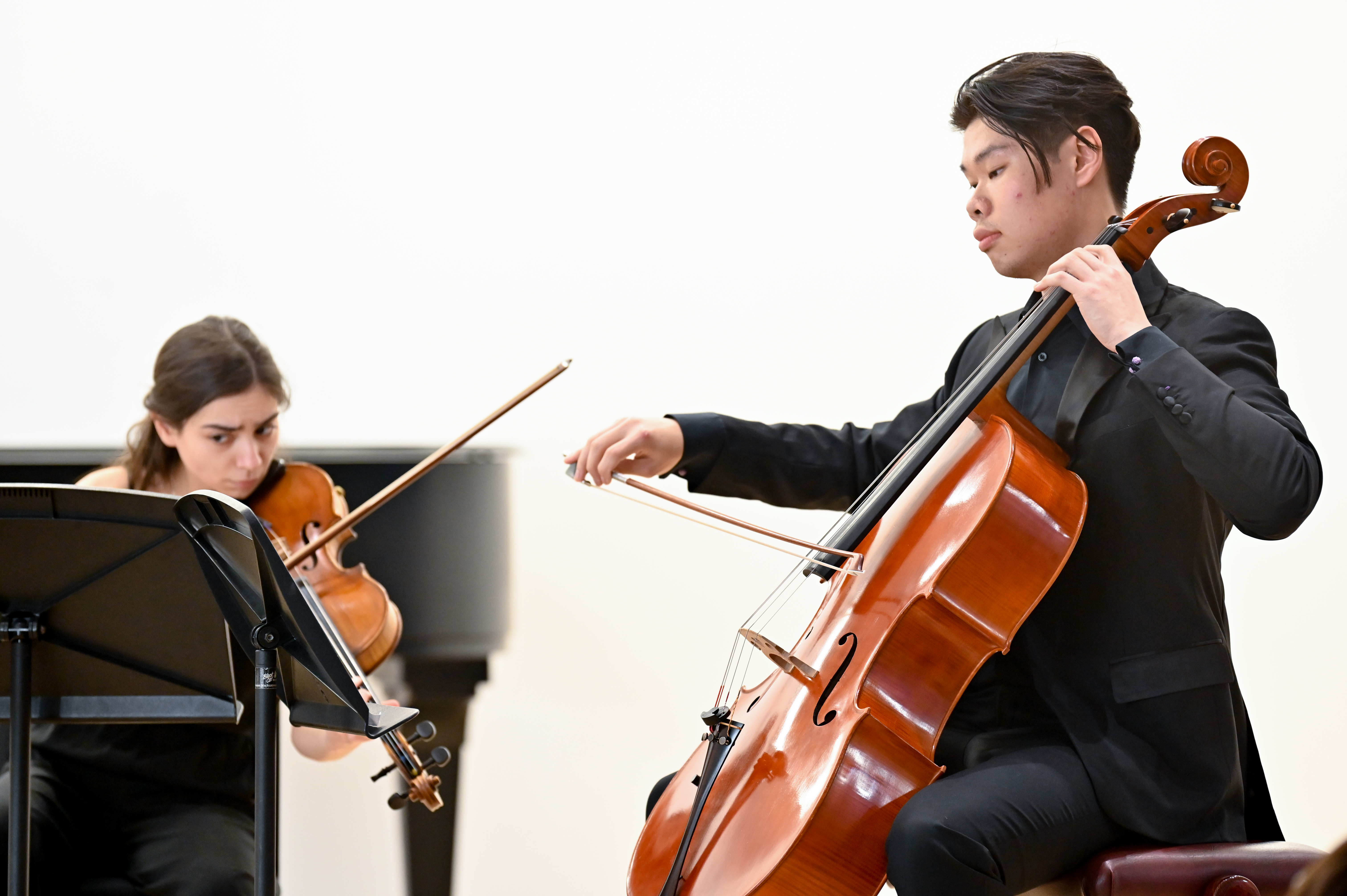A cellist and violinst perform together as part of a piano trio