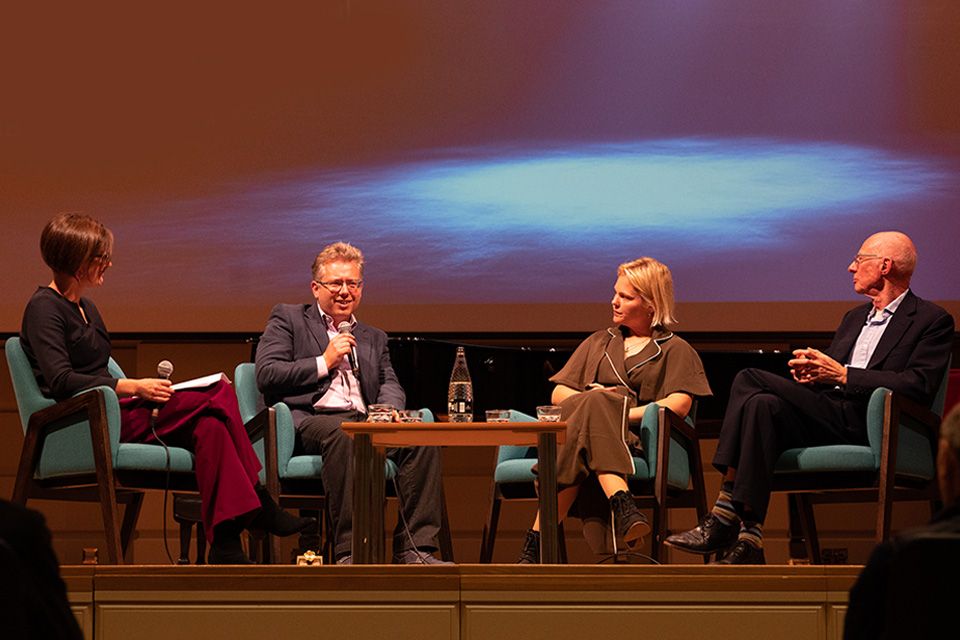 Four panelists from RCM and Imperial sit on a stage
