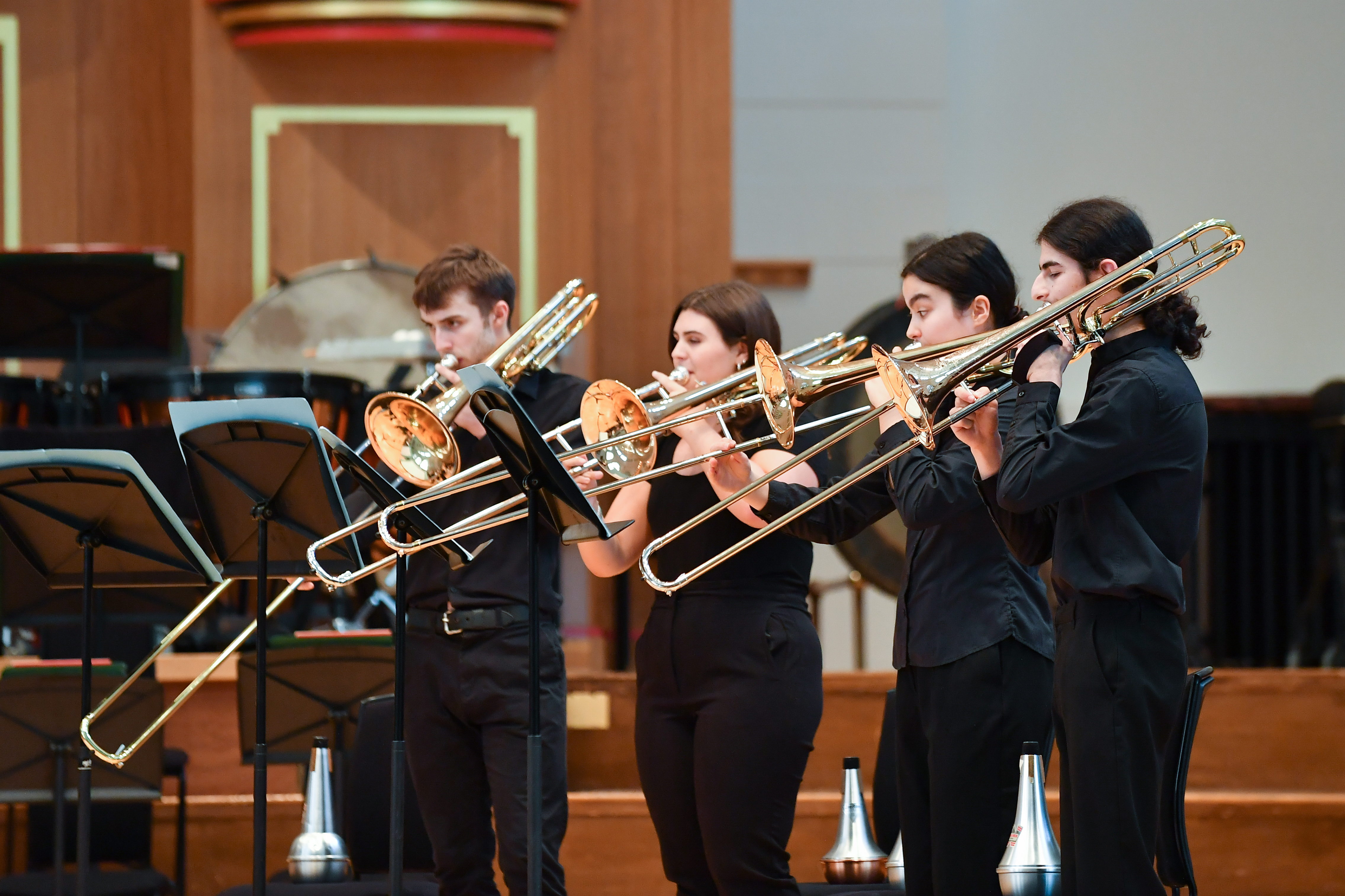 Four trombone players from the Junior Department performing in the Concert Hall