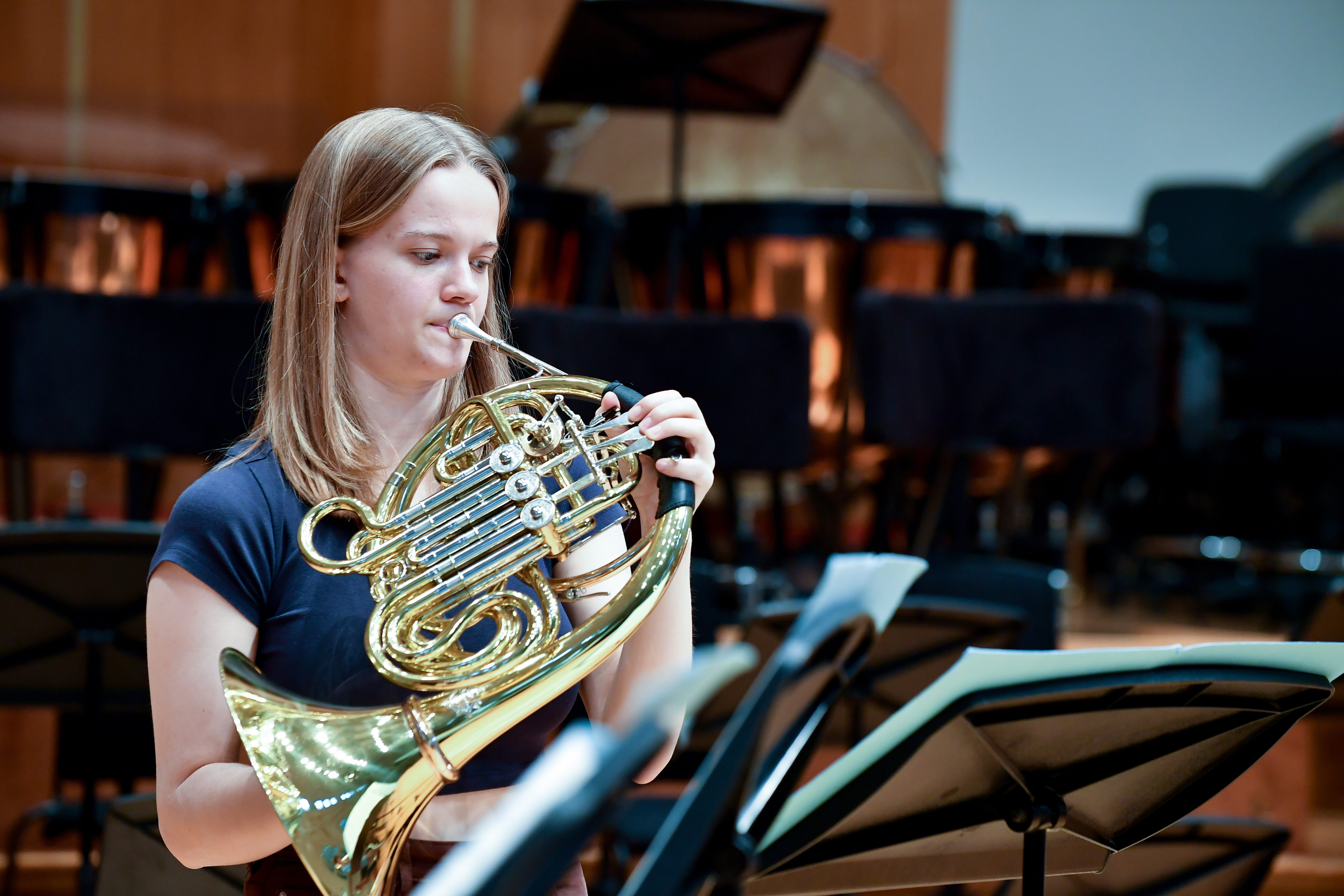 A girl from the Junior Department plays a French horn on stage