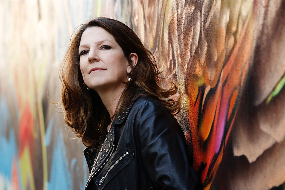 Susan Manoff stand in front of a colourful background