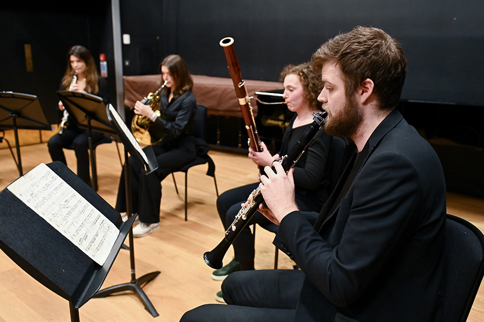 A quintet of musicians playing woodwind instruments perfom onstage