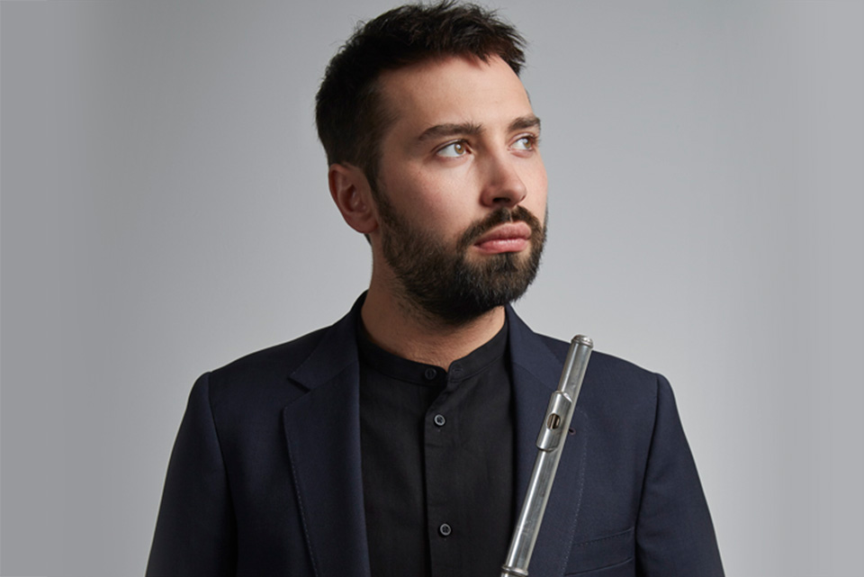 Flautist Adam Walker, pictured in front of a plain grey background