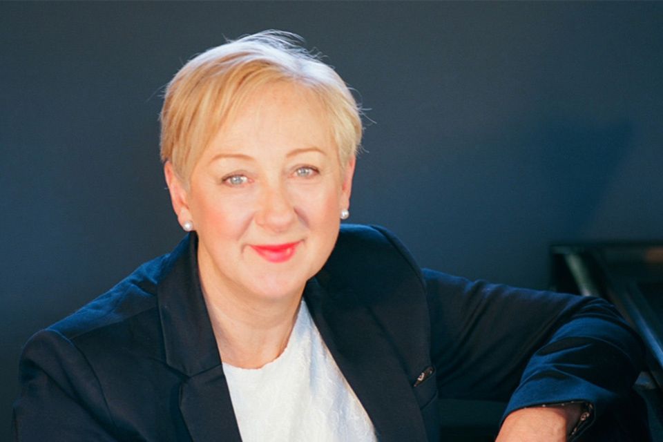 Audrey Hyland sits at the piano against a blue background