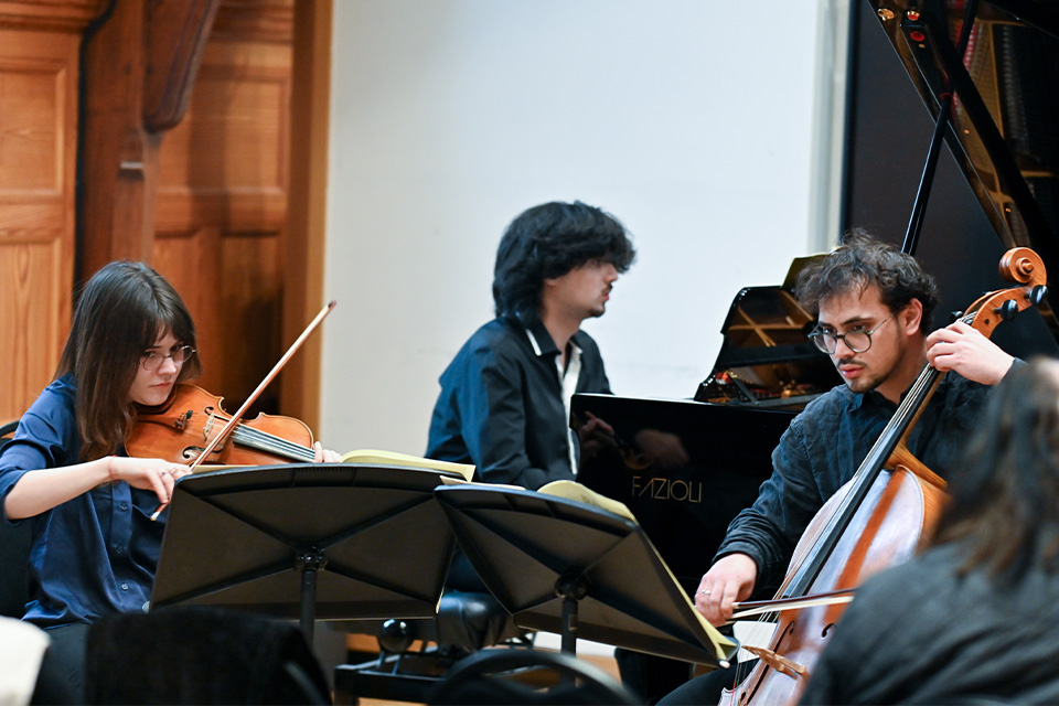 A pianist, violinist and cello perform in the Carne Room