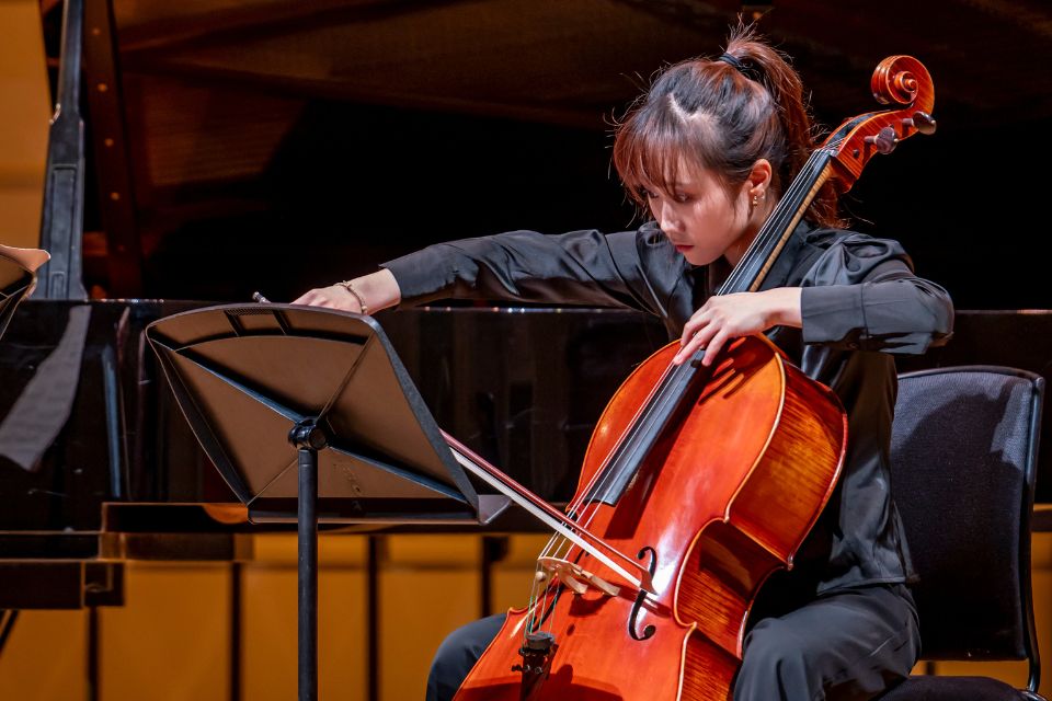 A young woman plays the cello expressively on stage