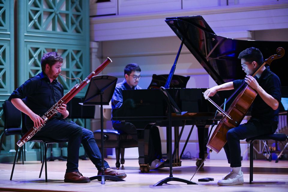 A chamber group perform on a dark stage lit up in blue and green