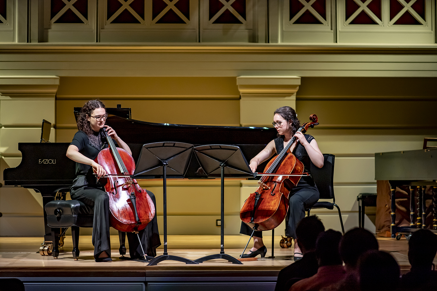 Two cellists performing on their instruments in the RCM Performance Hall