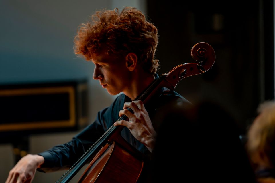 A cellist performs in a darkly lit room