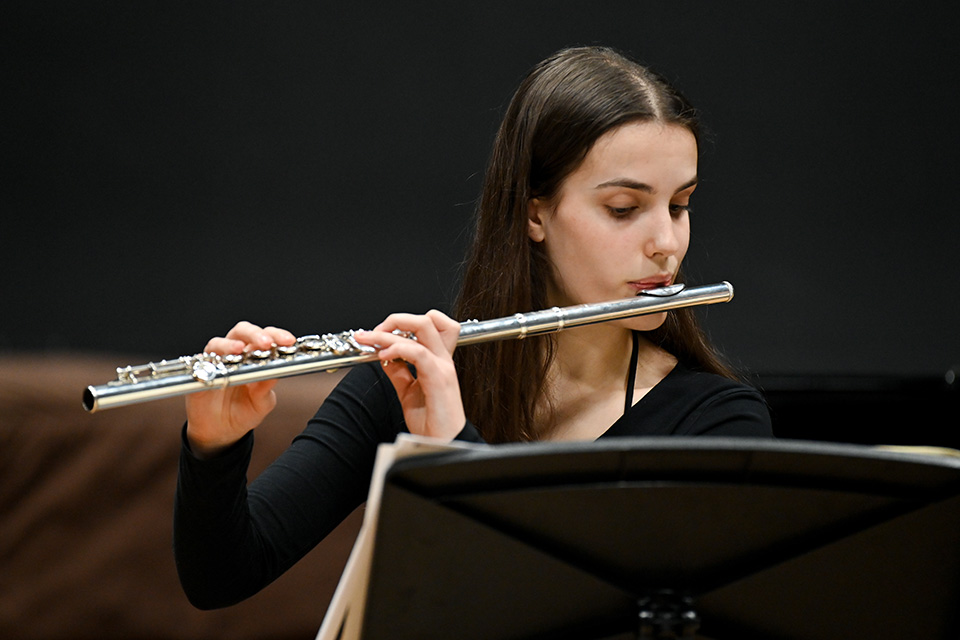 A flutist performing against a black background