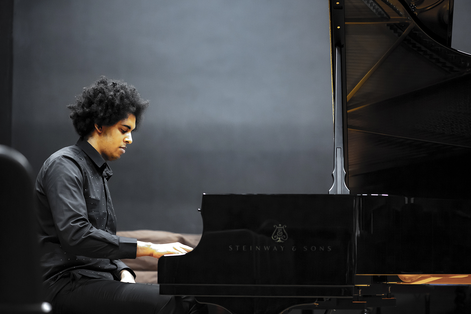 A man wearing black performs on a piano in the Performance Studio