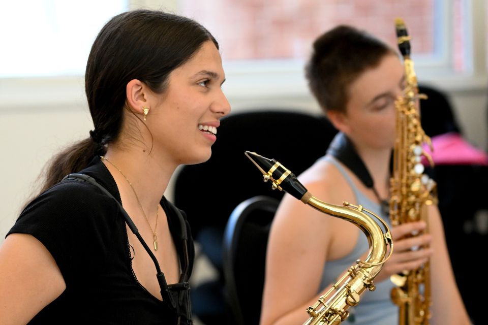 Two saxophonists smile holding their instruments