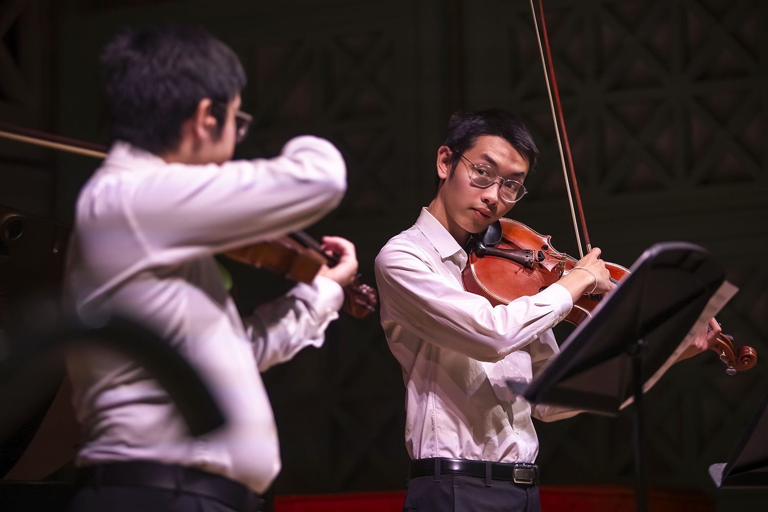 Two violinists wearing white shirts performing on stage