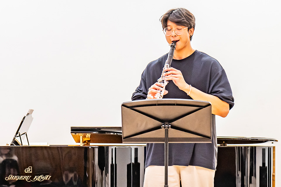 A clarinetist performs on a brightly lit stage