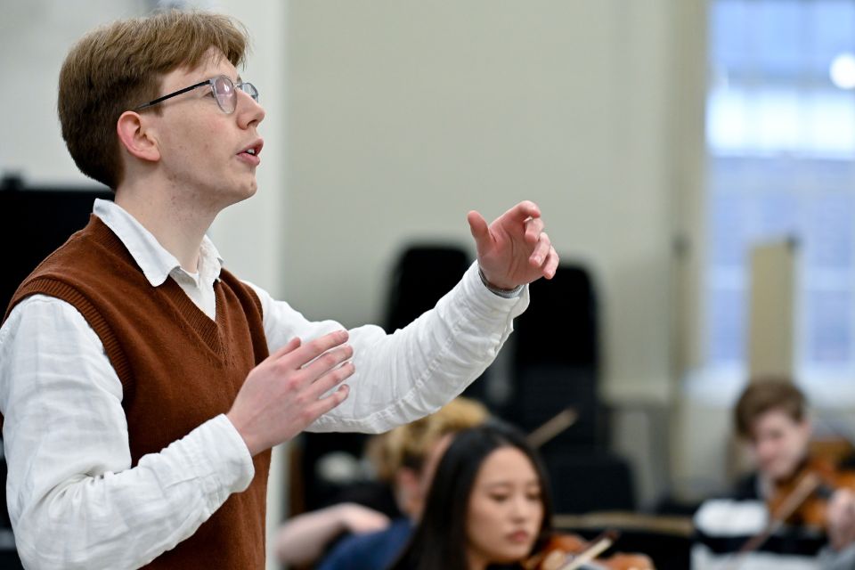 A young man conducts an orchestra