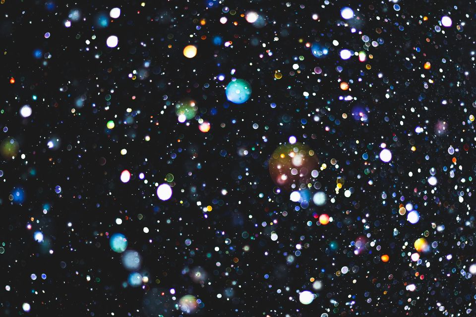 Multi-coloured sparkles glitter on a dark background