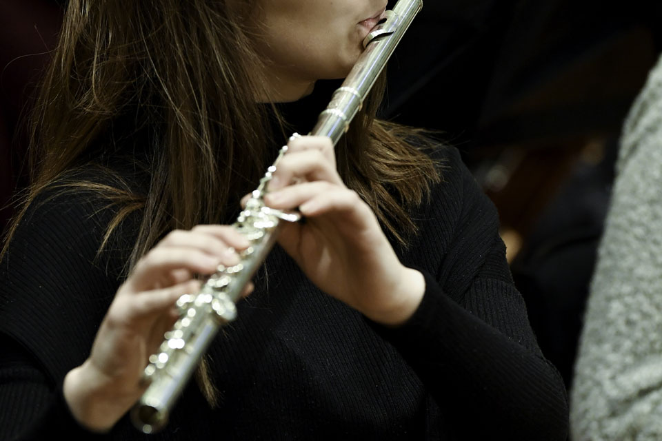 A close up of a woman wearing a black top playing the flute