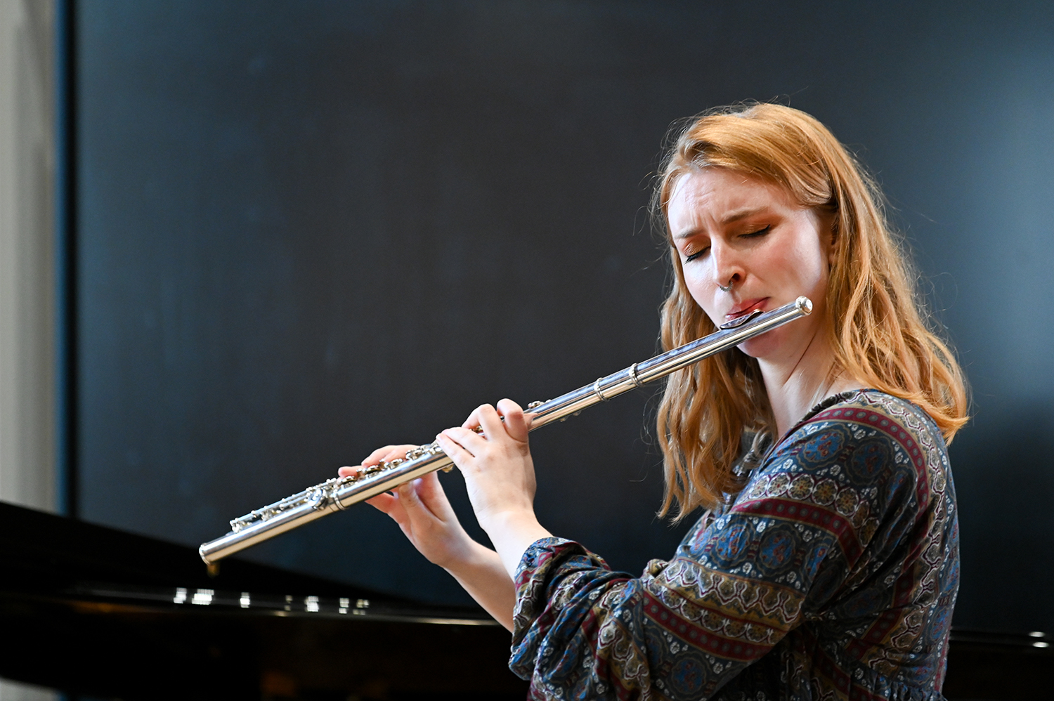 A woman with closed eyes performing on the flute