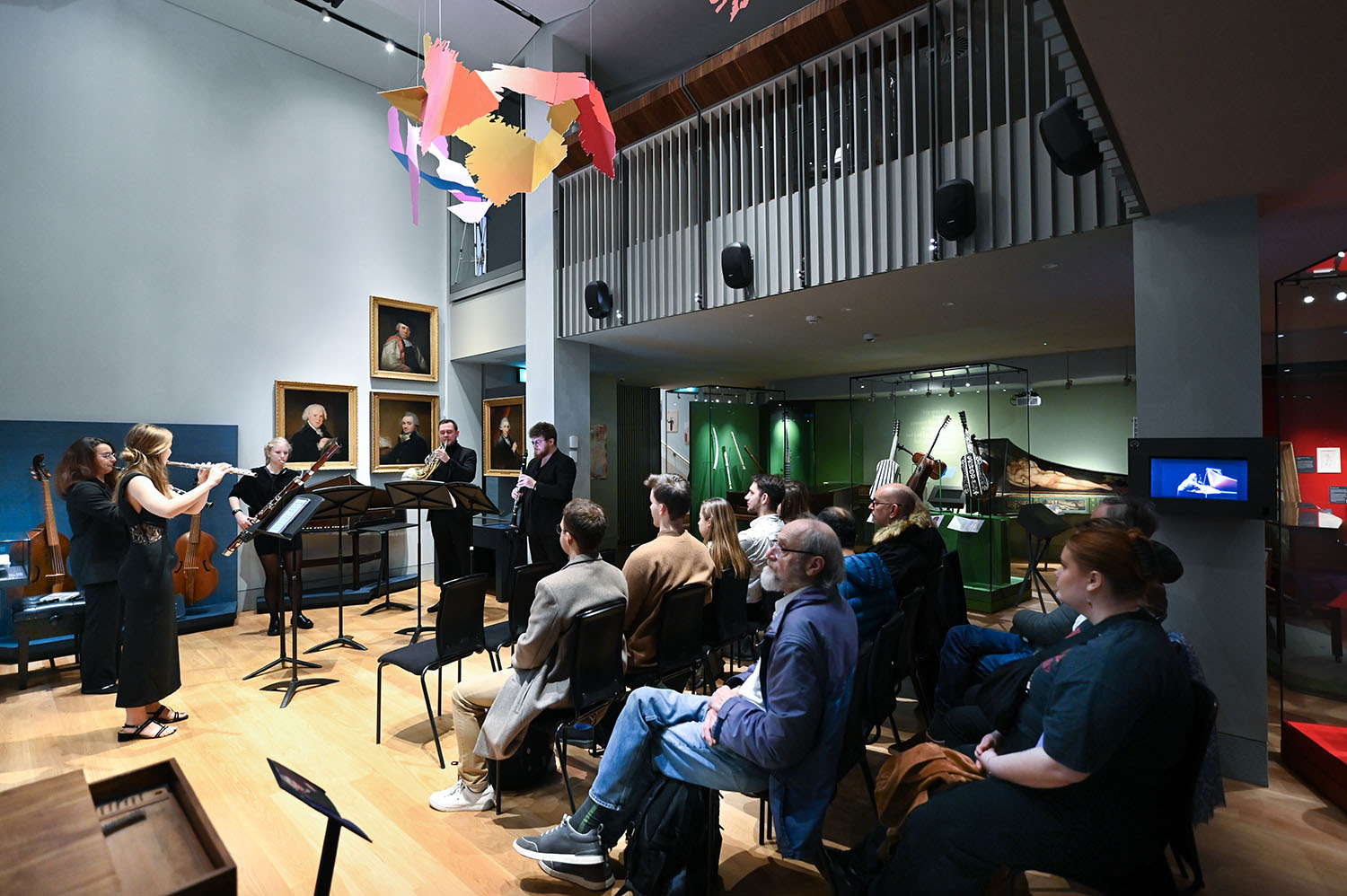 A group of chamber musicians performing to a full audience in the RCM Museum