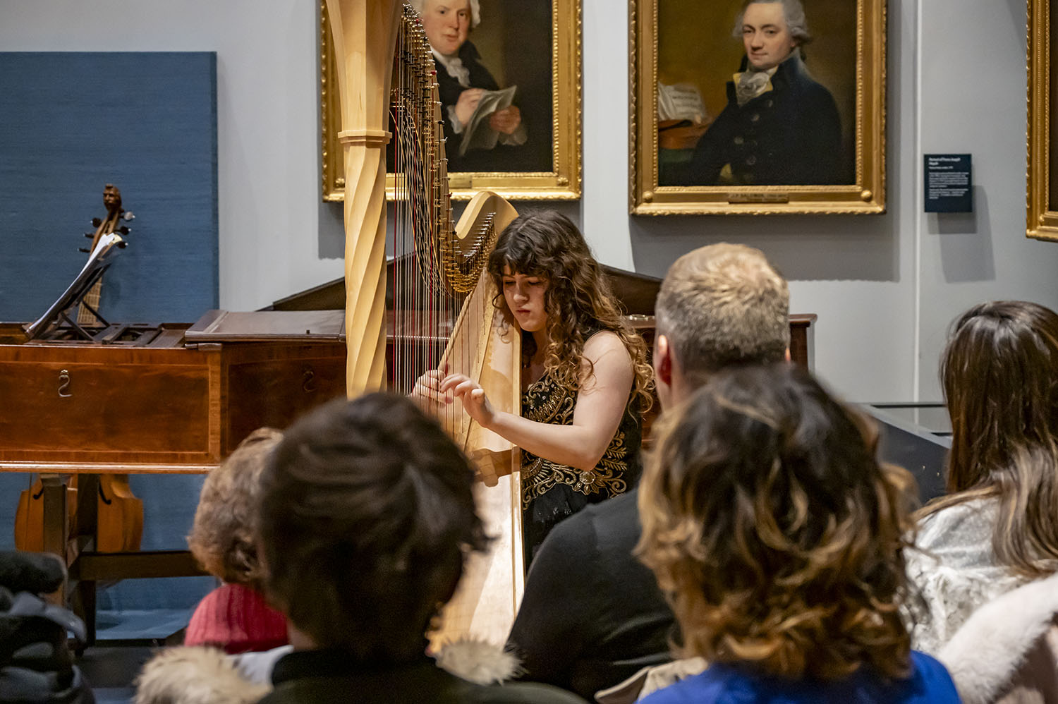A harpist performing to an audience in the RCM Museum