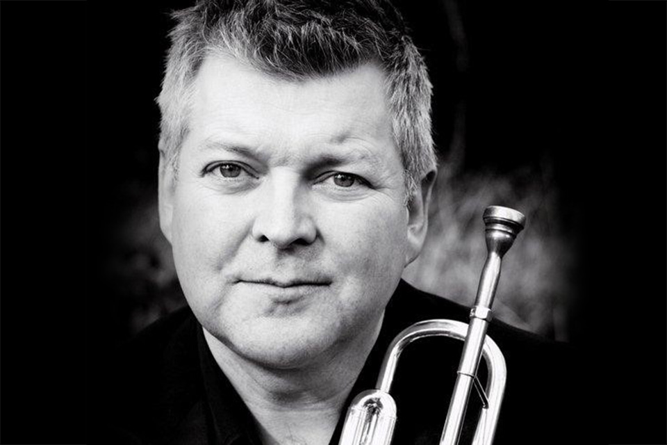 A black and white close-up photo of Gareth Small holding a trumpet
