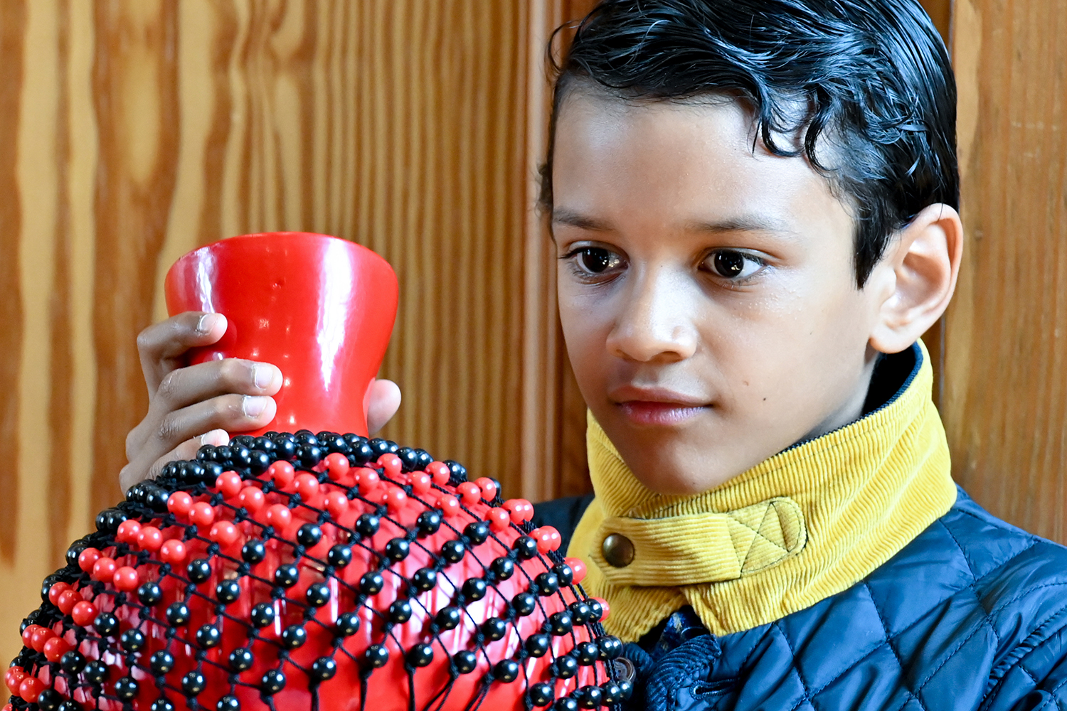 A close up of a little boy holding a percussion instrument