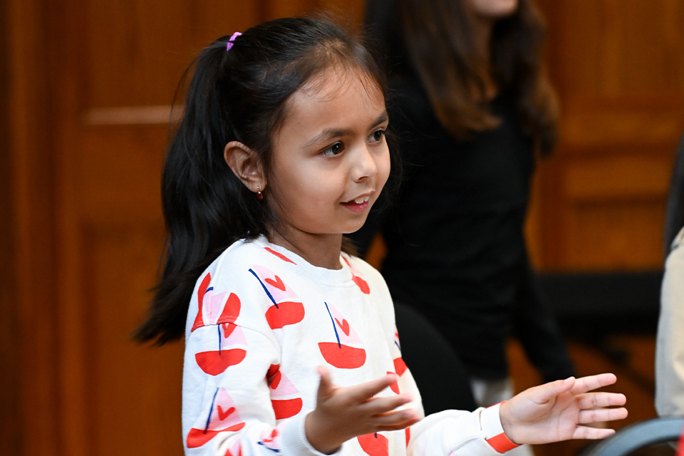 A young girl plays the drum, smiling
