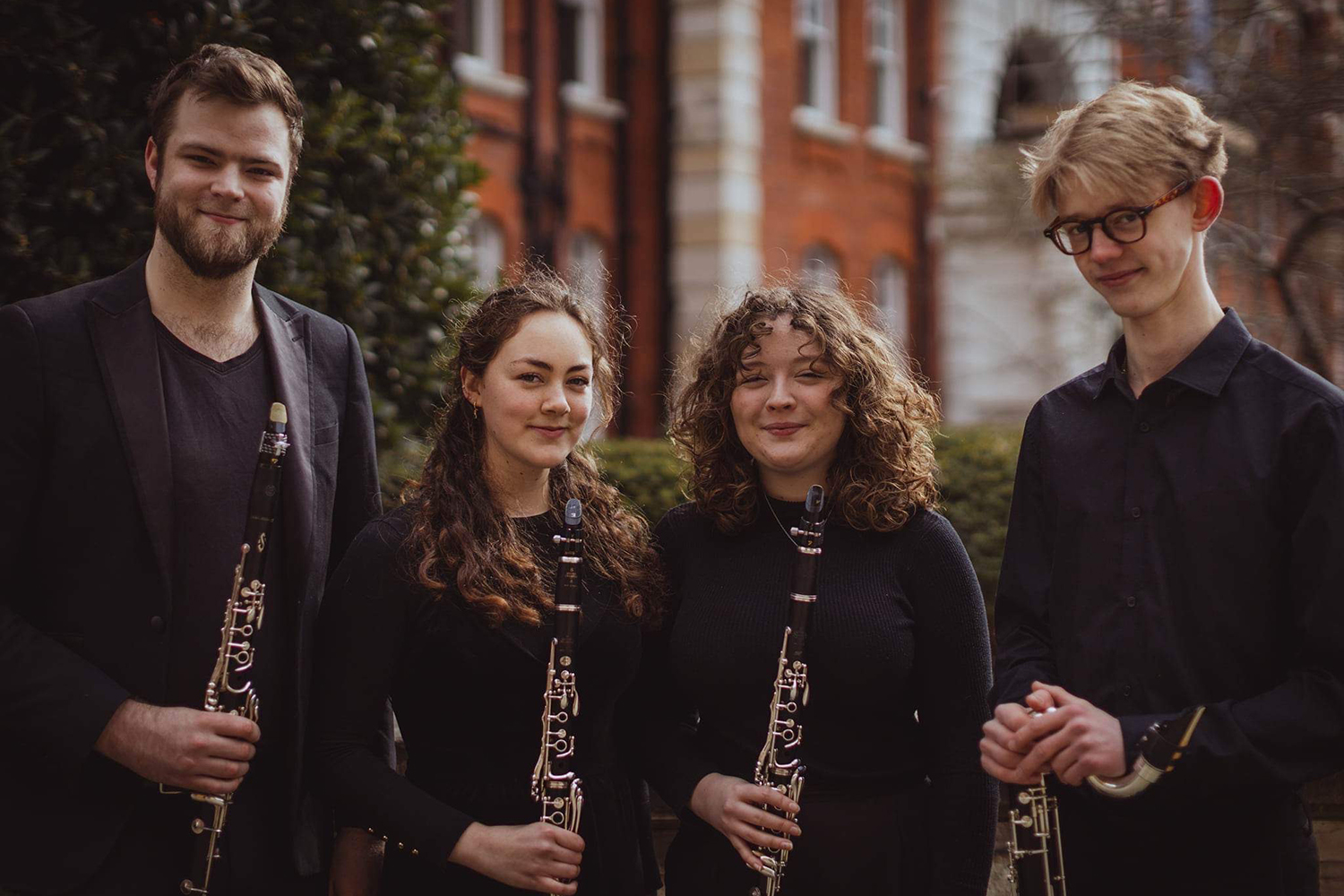 Four musicians wearing black and holding clarinets