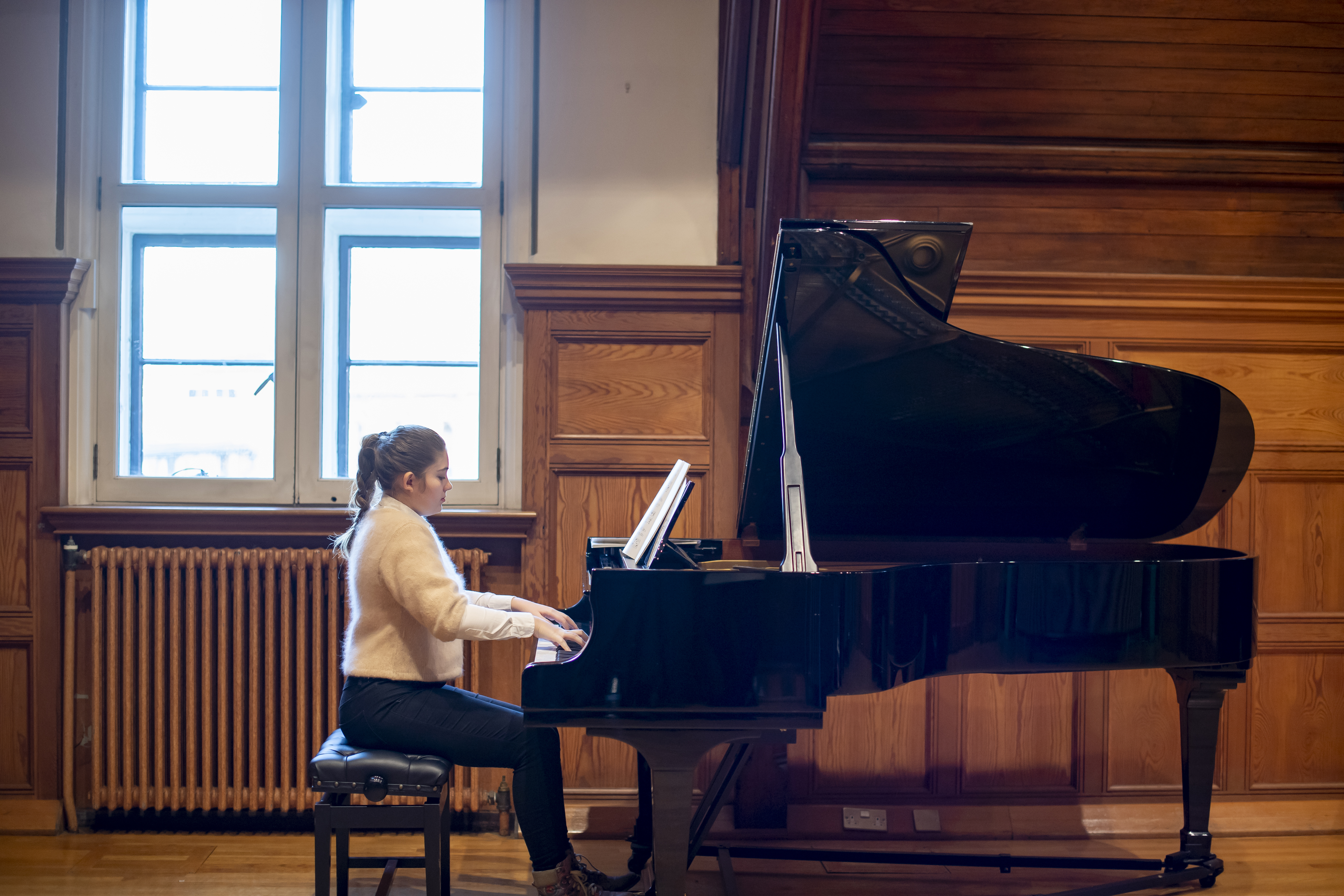 A student playing the piano in the Parry Room