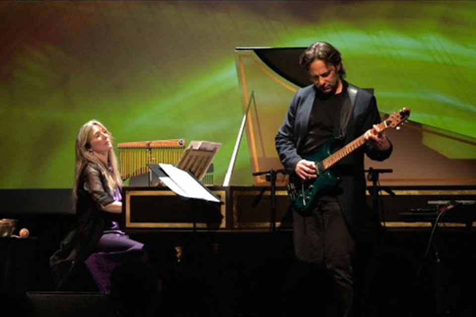 Jane Chapman playing a harpsichord on stage with a guitarist