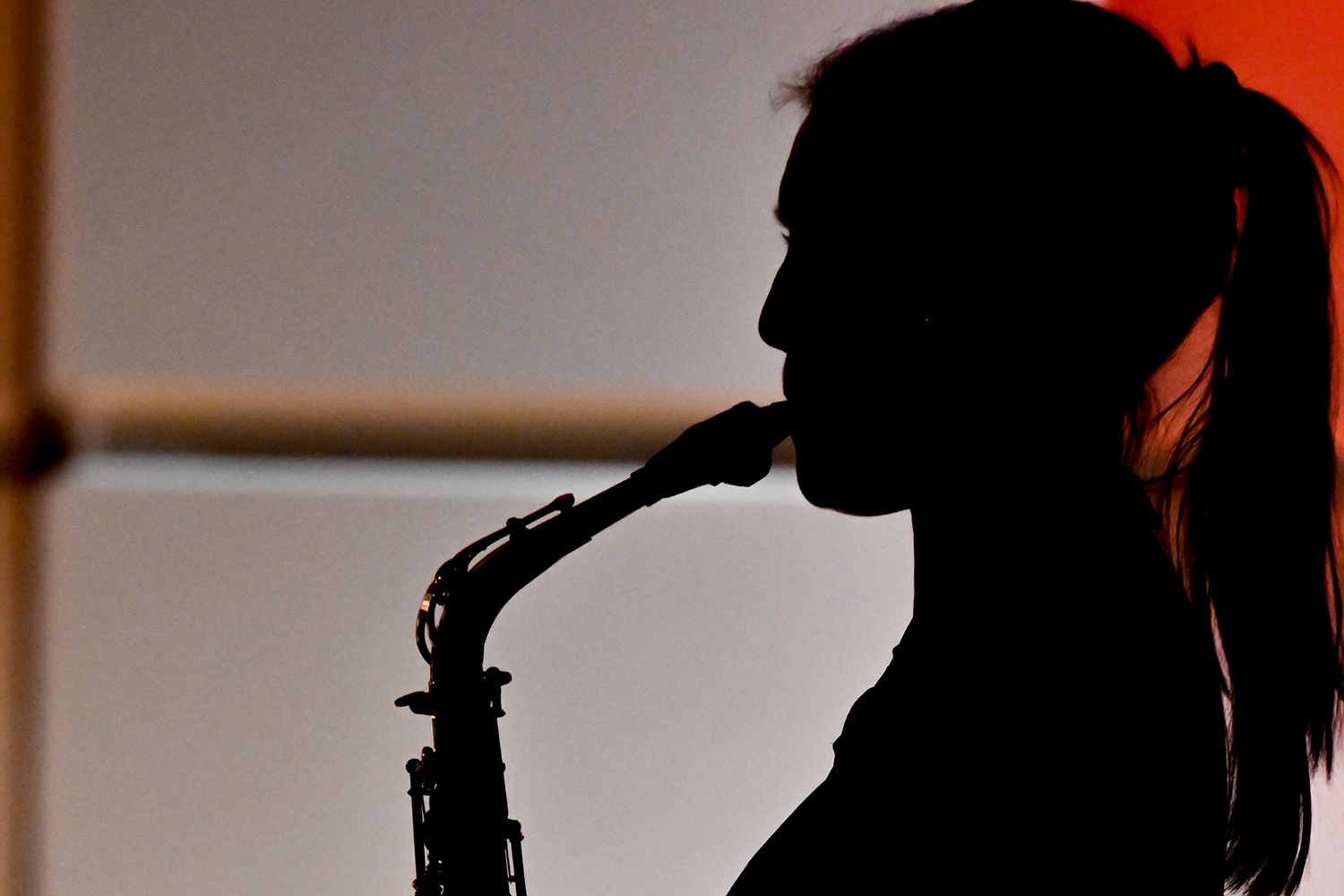 A silhouette of a woman performing on a saxophone
