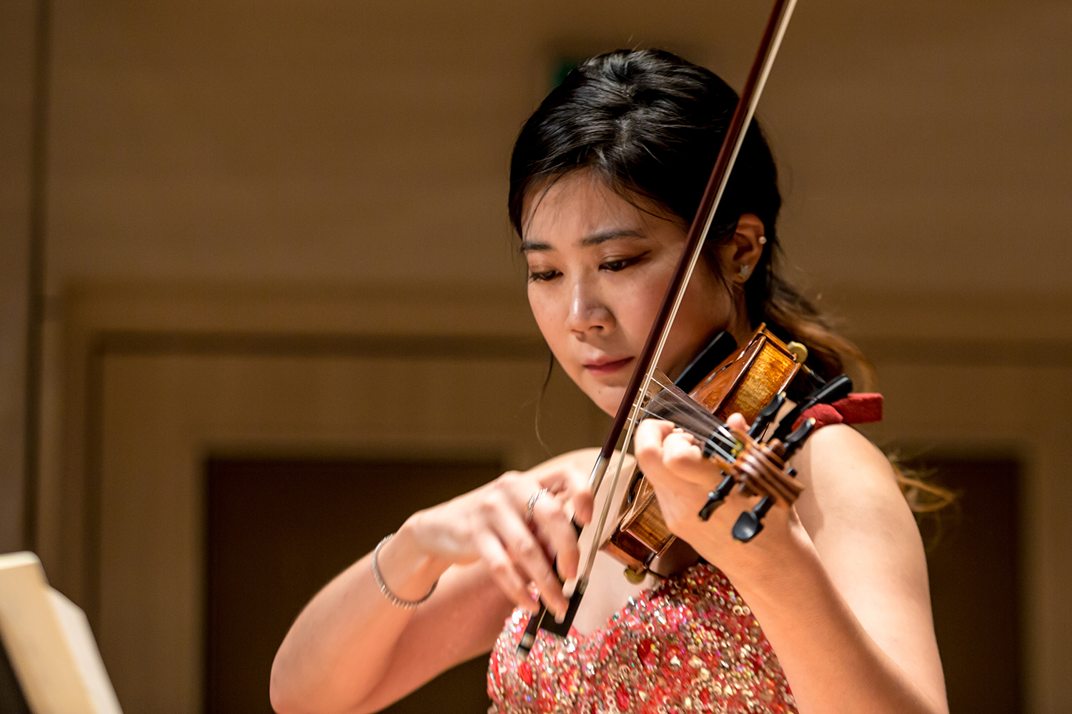 A close up photo of a woman performing on a violin in a concert hall