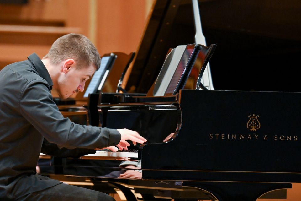 A young man plays the piano passionately on stage
