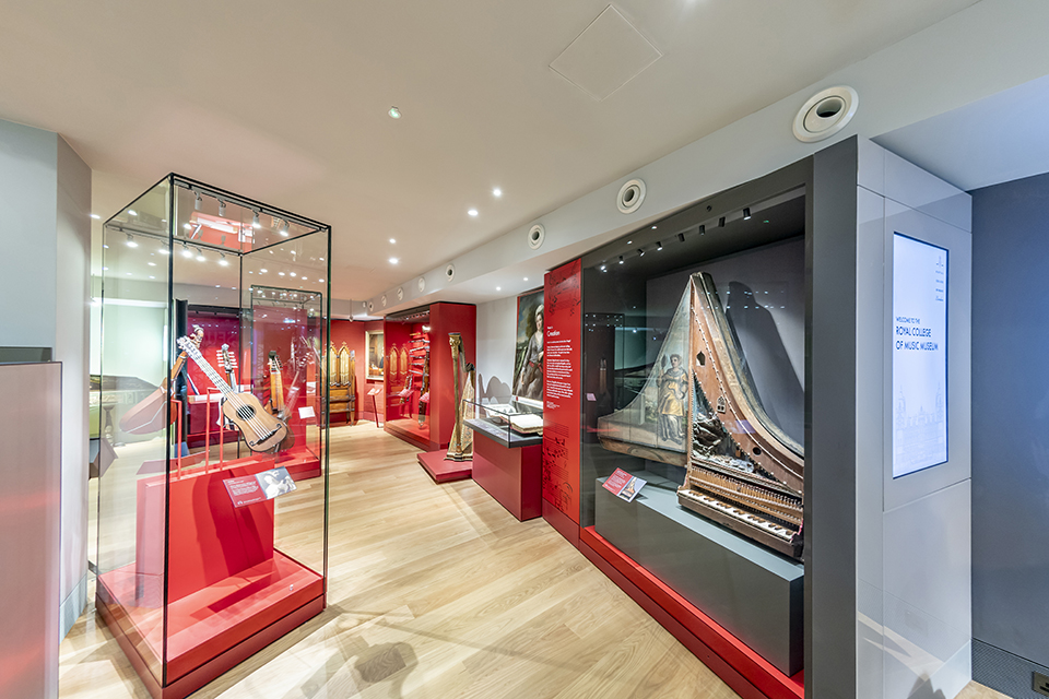 Display cases in the RCM Museum showing historic guitars, harpsichords and harps