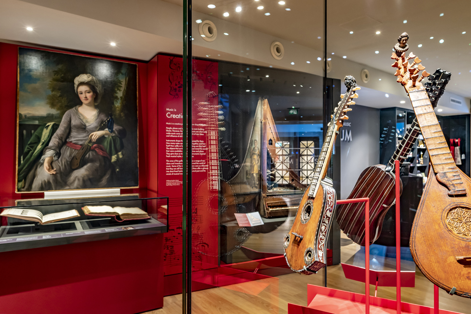 Display cases in the RCM Museum, showing historic guitars and paintings