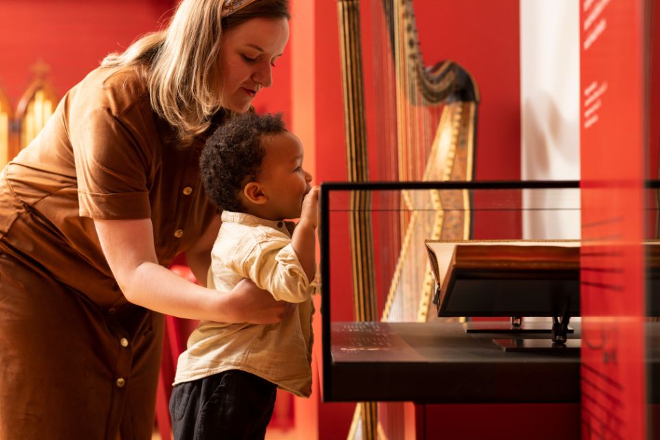 A mother holds her young child as he looks into a display case at the RCM Museum