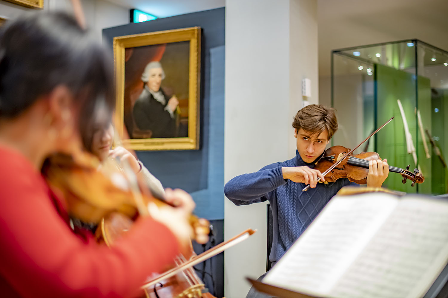 Three violinists performing in the Royal College of Music Museum