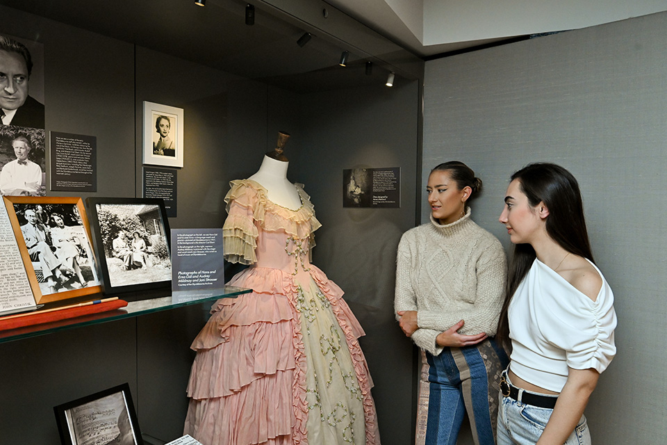 Two people look at a historical dress in a display case