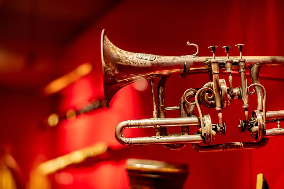 A historic trumpet displayed in the RCM Museum against a red background