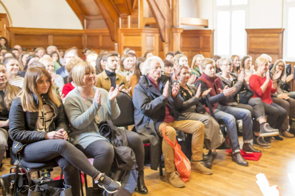 Seated audience members at a Royal College of Music event give a round of applause