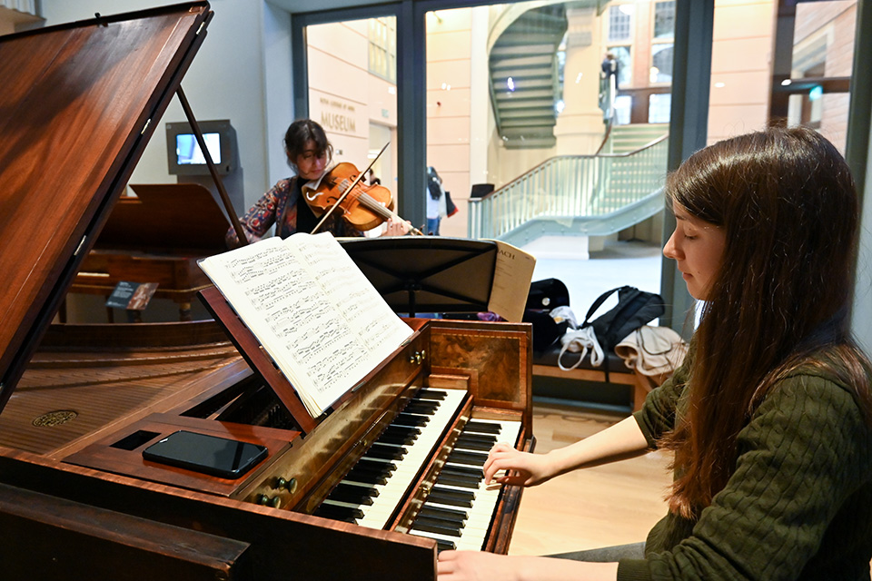 Two students perform on a harpsichord and a historical violin in the Royal College of Music Museum