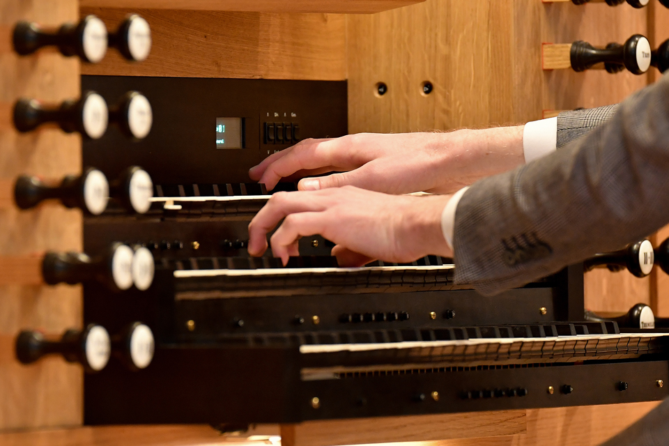 A close up image shows a student playing the Flentrop Orgelbouw organ at the RCM