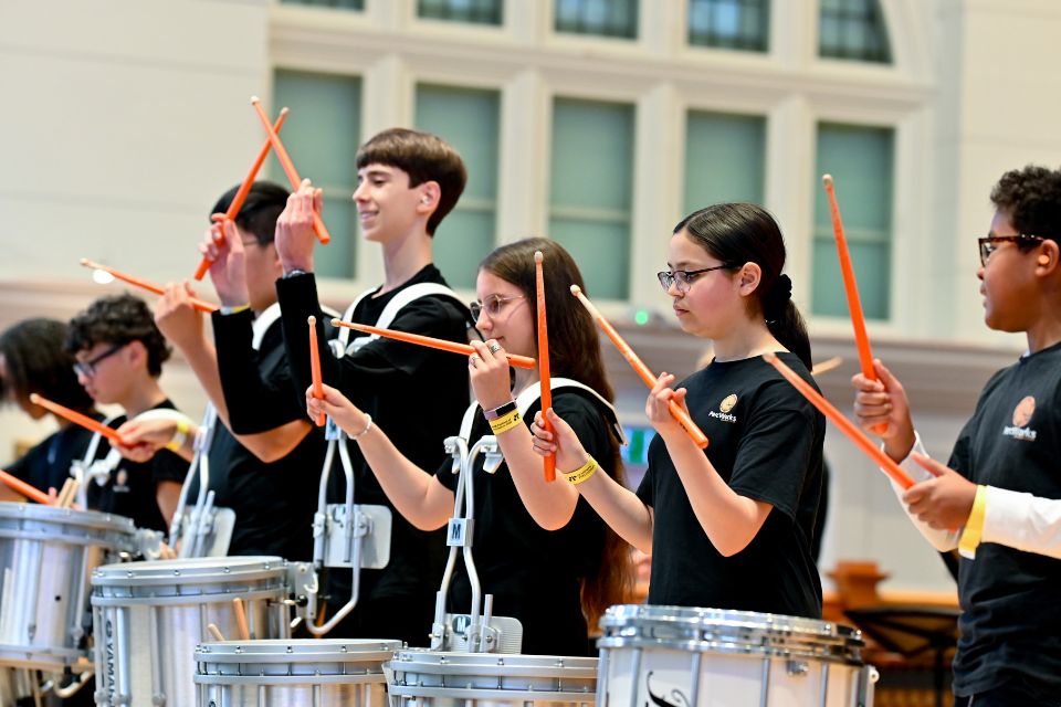 A group of young percussionists perform on stage