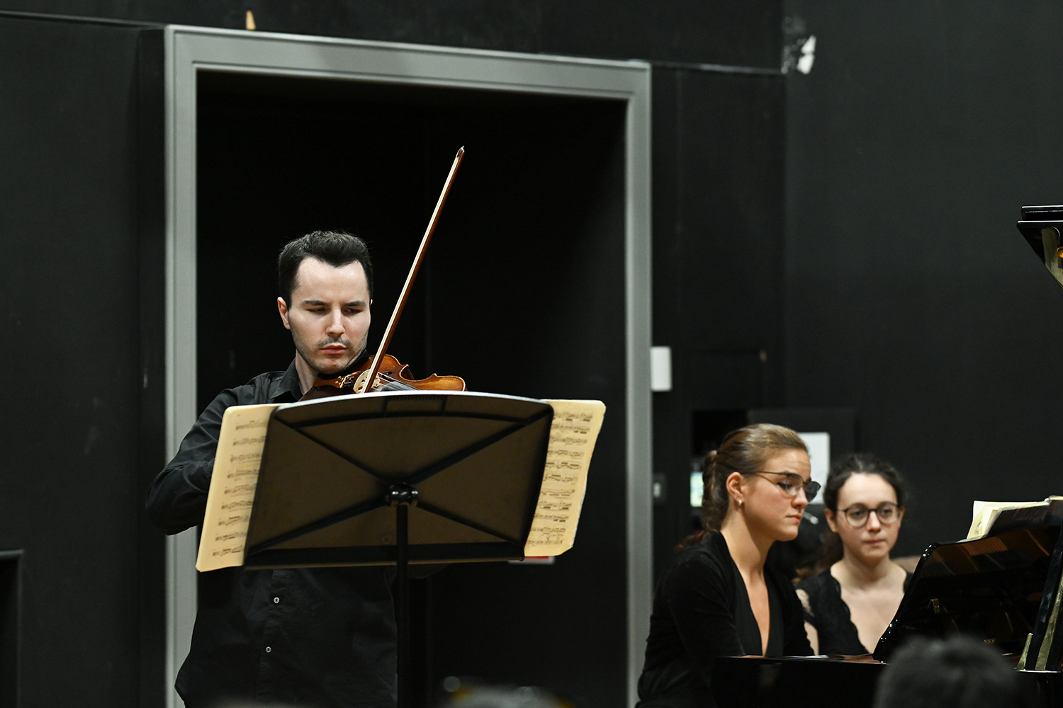 A man performs on a violin in the Performance Studio with a piano accompaniment 