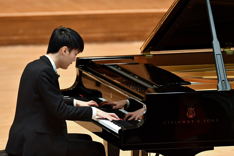 A pianist in black tie attire playing the grand piano